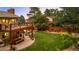 Lush backyard with an elevated deck, outdoor kitchen, seating, fire pit, and garden beds at 11796 W 53Rd Pl, Arvada, CO 80002