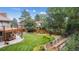 Beautiful backyard with lush green lawn, wooden deck, mature trees, and landscaped garden beds at 11796 W 53Rd Pl, Arvada, CO 80002
