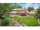 Expansive backyard featuring a lush lawn, mature trees, wooden deck, and a charming bridge over a small creek at 11796 W 53Rd Pl, Arvada, CO 80002
