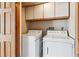 Functional laundry area featuring a side-by-side washer and dryer and white storage cabinets at 7696 S Monaco E Cir, Centennial, CO 80112