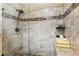 Elegant shower with a glass door, tiled walls, and a built-in seat with neatly stacked towels at 7696 S Monaco E Cir, Centennial, CO 80112