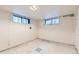 An empty basement with a tiled floor and two windows at 2866 Bellaire St, Denver, CO 80207