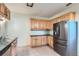 Kitchen featuring wooden cabinets, tiled floor, black countertops, and stainless steel refrigerator at 2866 Bellaire St, Denver, CO 80207