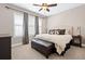 This spacious bedroom features a ceiling fan, three windows, and a large bed with an upholstered headboard at 10662 Skydance Dr, Highlands Ranch, CO 80126