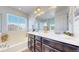 Well-lit bathroom featuring double sinks, a soaking tub, marble counters, and dark cabinetry at 10016 Hough Pt, Parker, CO 80134