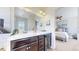 Bathroom featuring double sinks, granite counters, dark cabinets, and a view into the primary bedroom at 10016 Hough Pt, Parker, CO 80134