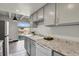 Galley kitchen featuring gray cabinets, granite countertops, white appliances, and access to a balcony at 100 S Clarkson St # 303, Denver, CO 80209