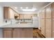Kitchen with wood cabinets, white appliances, laminate countertops, and natural lighting at 1050 S Monaco Pkwy # 77, Denver, CO 80224