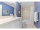 Bathroom with a blue wall, white single sink vanity, commode and shower over tub combination at 120 S Locust St, Denver, CO 80224