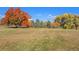 Expansive community grounds with mature trees displaying vibrant fall colors against a bright blue sky at 120 S Locust St, Denver, CO 80224