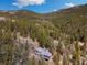 Stunning aerial view of a log cabin home surrounded by lush green forest, mountains in the background at 39 Pat Creek Rd, Evergreen, CO 80439