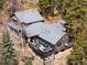 Aerial view of log cabin with multiple outdoor living spaces, mature trees, and stone accents at 39 Pat Creek Rd, Evergreen, CO 80439