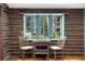 Cozy dining area with log walls, wood floors, and a large window with views of the lush greenery at 39 Pat Creek Rd, Evergreen, CO 80439