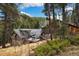 Picturesque log cabin home featuring a deck, outdoor seating, and surrounded by lush greenery and trees at 39 Pat Creek Rd, Evergreen, CO 80439