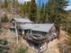 Beautiful log cabin home with a spacious deck, outdoor seating, and scenic views of surrounding trees at 39 Pat Creek Rd, Evergreen, CO 80439
