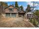 Charming log cabin home with a two-car garage, stone accents and mature trees in the background at 39 Pat Creek Rd, Evergreen, CO 80439