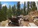 Inviting outdoor fire pit area with wooden Adirondack chairs surrounded by towering trees at 39 Pat Creek Rd, Evergreen, CO 80439