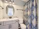 Bathroom with a modern vanity, granite countertop, round mirror, and patterned shower curtain at 9813 E Carolina Pl, Aurora, CO 80247