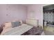 A cozy bedroom featuring lavender walls, a dresser, and a view into the bathroom at 9996 Sedalia St, Commerce City, CO 80022