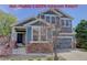Charming two-story blue home featuring a stone facade and well-maintained landscaping at 9996 Sedalia St, Commerce City, CO 80022