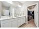 Bathroom with double sinks, white cabinets, and access to a walk-in closet at 8888 Falcon St, Longmont, CO 80504