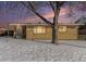 Brick ranch home with snowy yard, illuminated at dusk at 7674 Stuart St, Westminster, CO 80030