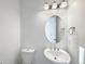 Well-lit powder room with a modern round mirror, stylish vanity, and a convenient toilet at 3520 Little Bell Dr, Frederick, CO 80516