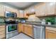 Close-up of the kitchen boasting stainless steel appliances, ample counter space, and natural wood cabinetry at 610 S Clinton St # 3D, Denver, CO 80247
