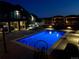A lighted backyard features a pristine pool, an outdoor seating, and a well-maintained yard at twilight at 1063 Clarke Ct, Castle Rock, CO 80109