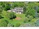 This aerial view highlights the home with a large lawn and wooded area surrounding it at 9678 E Powers Dr, Greenwood Village, CO 80111