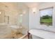 Bright bathroom featuring glass enclosed shower, soaking tub, and large window with backyard view at 9678 E Powers Dr, Greenwood Village, CO 80111
