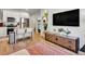 Open-concept living room features a modern TV console, wood floors, and updated kitchen at 1303 Jersey St, Denver, CO 80220