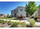 Inviting two-story townhome featuring stone accents, lush landscaping, and a well-maintained walkway at 952 Morning Glory Rd, Brighton, CO 80640