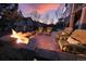 Backyard patio with comfortable chairs around a cozy brick fire pit, perfect for relaxation under a gorgeous sunset at 23426 E Ottawa Dr, Aurora, CO 80016