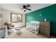 Bright bedroom with a white crib, rocker, and green accent wall providing a cozy and inviting atmosphere at 4620 W 108Th Pl, Westminster, CO 80031