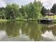 Scenic view of a serene lake with trees and a wooden dock, reflecting the peaceful surroundings at 23846 Genesee Village Rd, Golden, CO 80401