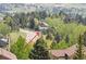 A hilltop home among green trees shows the lovely surrounding neighborhood at 23846 Genesee Village Rd, Golden, CO 80401