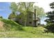 Rear exterior view showing a multi-level deck, yard with mature landscaping and a sloped lot at 23846 Genesee Village Rd, Golden, CO 80401