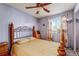 Cozy bedroom featuring a ceiling fan, a decorative headboard, and a large window with floral curtains at 16980 E Stanford Ave, Aurora, CO 80015
