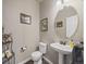 A stylish powder room with a pedestal sink, round mirror, and decorative accents at 6432 S Robb Ct, Littleton, CO 80127