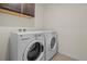 Convenient laundry room featuring modern washer and dryer appliances under a shelf at 14912 Vienna Cir, Parker, CO 80134