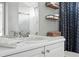 Bright bathroom features a white vanity, open shelves and decorative blue shower curtain at 3543 Foxridge Trl, Highlands Ranch, CO 80126