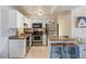 Well-lit kitchen with white cabinetry, stainless steel appliances, breakfast bar, and tile floors at 5300 E Cherry Creek South Dr # 124, Denver, CO 80246