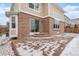 A brick home exterior with a stamped concrete patio dusted with snow, accessible through sliding glass doors at 24285 E Wagontrail Ave, Aurora, CO 80016