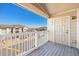 Cozy balcony space featuring a wooden floor, white railing, and neighborhood views under a blue sky at 5756 N Genoa Way # 12-305, Aurora, CO 80019