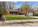 Charming two-story home featuring a brick facade, lush lawn, mature trees, and a driveway leading to an attached garage at 6247 S Locust St, Centennial, CO 80111