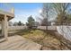 View of a partially shaded backyard featuring a concrete patio, a swing, and a white picket fence at 4787 Dunkirk St, Denver, CO 80249