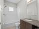 This bathroom features a neutral vanity, modern sink, and a white tiled shower-tub combo with a glass shower door at 1996 W 66Th Ave, Denver, CO 80221