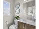 This bathroom features a white toilet, modern vanity, sleek faucet, and decorative circular mirrors at 1996 W 66Th Ave, Denver, CO 80221