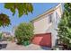 Spacious two-car garage with a red door, surrounded by mature trees and greenery at 1996 W 66Th Ave, Denver, CO 80221